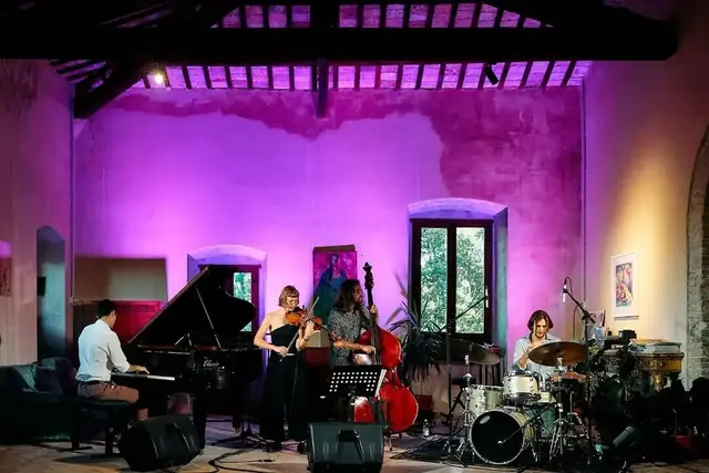 Il quartetto con il violino in una sala dalle pareti illuminate di viola